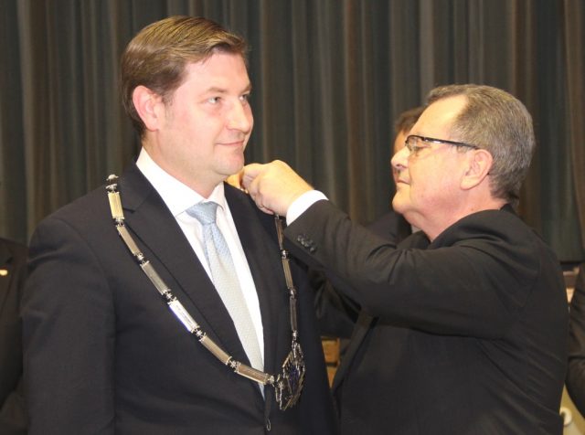 Bürgermeister Ernst Lauterjung (SPD) legt Tim Kurzbach die Amtskette des Oberbürgermeisters um. Vereidigt wurde der 38-Jährige am 29. Oktober letzten Jahres im der Ohligser Festhalle. (Archivfoto: B. Glumm)
