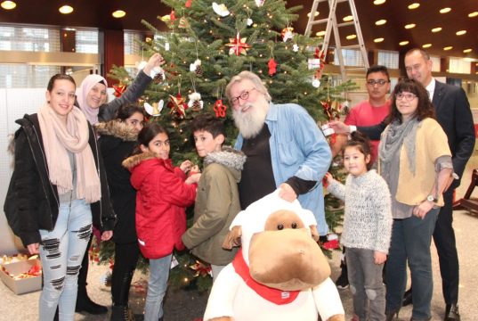 Hat gut lachen: Gunther "Felix" Opitz (mi.) am Mittwoch gemeinsam mit "seinen" Kids in der Kassenhalle der Hauptstelle der Stadt-Sparkasse Solingen. Geschmückt wurde dort der vier Meter hohe Weihnachtsbaum mit selbst gebasteltem Schmuck. Auch Sparkassen-Vorstand Stefan Grundwald (re.) half mit. (Foto: B. Glumm)