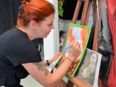 Bei der Vernissage führt Alexandra Keller live eine Airbrush-Arbeit vor. Nach dem Aufsprühen wird die Farbe partiell wieder entfernt, um anschließend mit Künstlerbuntstiften Akzente zu setzen. (Foto: © Martina Hörle)