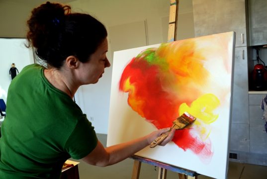 Silke Widenka experimentiert gerne mit Materialien, kombiniert Malstile. Hier trägt sie mit breitem Pinsel Acrylfarbe in geschwungenen Bahnen auf. (Foto: © Martina Hörle)