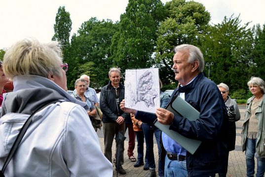 Die Exkursion durch Höhscheid beginnt auf dem Peter-Höfer-Platz. Axel Birkenbeul zeigt einen Plan über das ursprüngliche Höhscheider Gebiet. (Foto: © Martina Hörle)