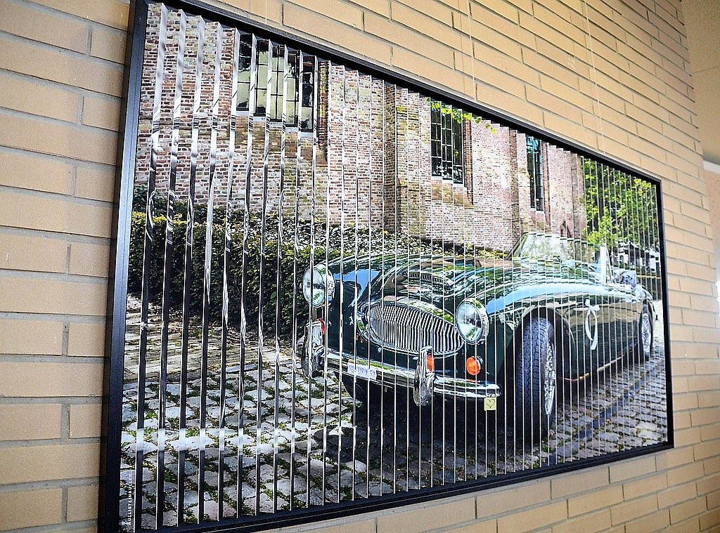 Das Auto ist eines der Zwei-Sicht-Bilder von Ulli Steinküller. Es trägt den Titel „Eine gescheiterte Beziehung“. Der Künstler hat Fotos in Streifen geschnitten und auf Alu-Schienen geklebt. Von der anderen Seite ändert sich die Ansicht total. Eine eindrucksvolle Arbeit. (Foto: © Martina Hörle)