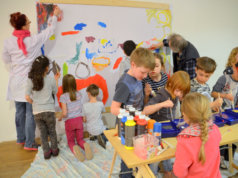 Gemeinsam mit den Künstlern Saskia Bela und Lothar Ruthmann gestalteten die Kinder der Grundschule Schützenstraße ein fröhliches und buntes Gemeinschaftswerk, das in Kürze auf dem Ferien(s)pass-Plakat zu sehen sein wird. (Foto: © Martina Hörle)