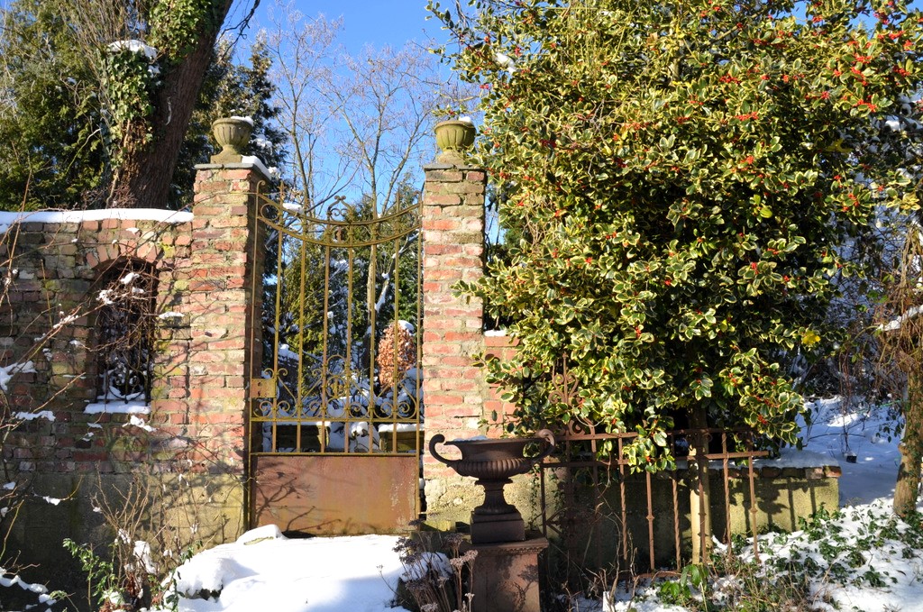 Das Tor, das aus dem Klostergarten hinausführt, wird von einer Rose und einem Ilex flankiert. Auf den Pfeilern stehen steinerne Pokale. (Foto: © Martina Hörle)