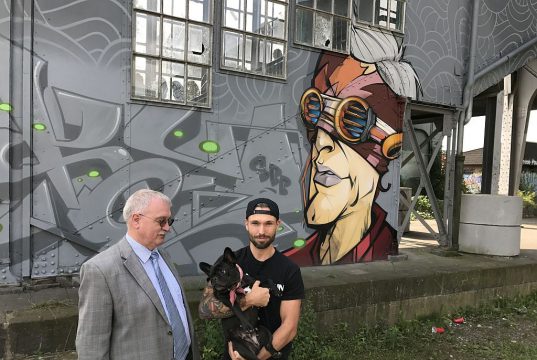 Bezirksbürgermeister Richard Schmidt (SPD) und Künstler Kayo Karacho vor dem neuen Graffito am Treppenaufgang zur Bahnhofsbrücke. Schmidt hat die Kostenübernahme für das Material zugesagt. Karacho konnte die Untere Denkmalbehörde mit seinen Entwürfen überzeugen. (Foto: © Petra Krötzsch)