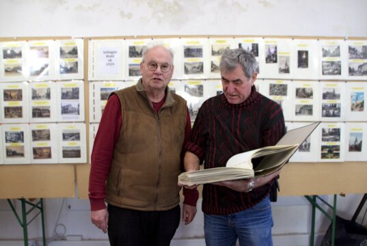 Wolfgang Müller (v. li.) und Werner Rühlke präsentieren zusammengetragene historische Dokumente über Wald. (Foto © Sarah Schmitz)