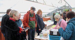 Ehrenamtlerin Verena Kara-Jahn (links) informierte die tauschfreudigen Besucher der Saatgutbörse über die Sämereien und vorgezogene Pflanzen. (Foto © Sarah Schmitz)