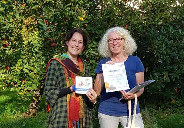 Annette Kalde (re.) vom NABU überreicht die Urkunde für den schmetterlingsfreundlichen Garten an Hobbygärtnerin Sarah Schmitz. (Foto: © Christoph Kalde)