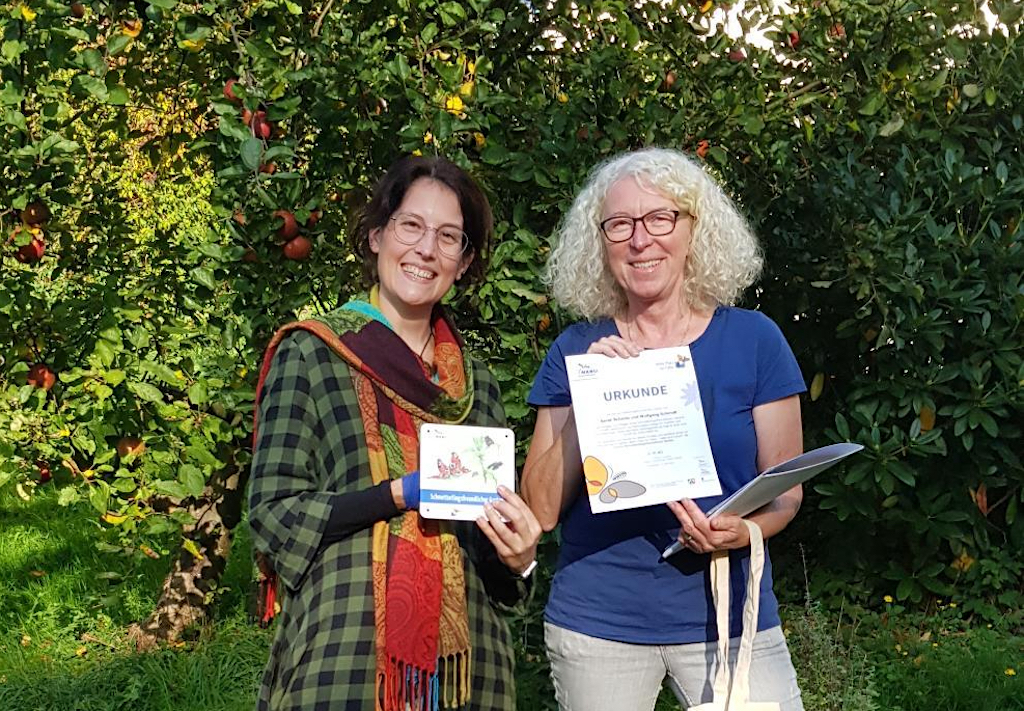 Annette Kalde (re.) vom NABU überreicht die Urkunde für den schmetterlingsfreundlichen Garten an Hobbygärtnerin Sarah Schmitz. (Foto: © Christoph Kalde)