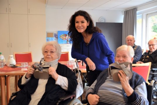 Heute übergaben Mariella Ahrens und Petra Krötzsch vom Verein Lebensherbst zwei VR-Brillen an die Bewohner der Senioreneinrichtung Bethanien. Hier probieren Ingrid Eberhard (li.) und Helma Warda (re.) die neuen Brillen aus. Schirmherrin Mariella Ahrens freut sich mit den beiden Seniorinnen. (Foto: © Martina Hörle)