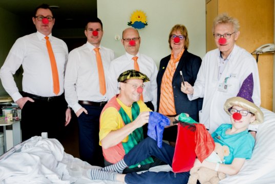 Den jungen Patienten Leander muntert der Besuch von Clown Ötti (Martin Wolff) auf. Mit dabei waren auch (v.l). Stefan Röhrig, Jörg Guardiera, Eric Brühne sowie Gudrun Berger von der Volksbank im Bergischen Land und Dr. Volker Soditt, Chefarzt der Klinik für Kinder- und Jugendmedizin im Klinikum Solingen. (Foto: © Volksbank/Anne Stahl)