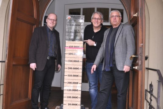 Pfarrer Matthias Clever, Baukirchmeister Joachim Buchmüller und Spendenteam-Leiter Ralf Puslat (von links) präsentierten jetzt die Spendensäule, die den Stand des Spendenaufkommens für die geplante Erweiterung und Modernisierung des Gemeindezentrums Christuskirche in Aufderhöhe anschaulich macht. (Foto: © Ev. Kirchengemeinde St. Reinoldi Rupelrath)