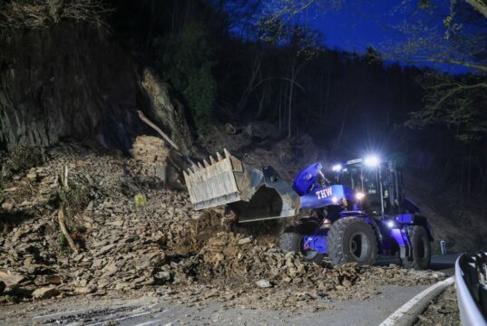 Ein Radlader des Technischen Hilfswerks räumt am Balkhauser Weg große Mengen Geröll und Felsmaterial von der Fahrbahn, nachdem sich mehrere Felsstücke aus dem Hang gelöst hatten. (Foto: © Tim Oelbermann)