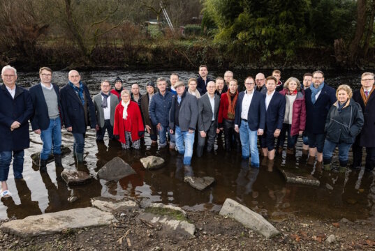 Über 20 Unternehmerinnen und Unternehmer aus dem Bergischen Städtedreieck stehen symbolisch in der Wupper, um auf die angespannte wirtschaftliche Lage der Industrie und den aus ihrer Sicht wachsenden Handlungsdruck für Politik und Verwaltung aufmerksam zu machen. (Foto: © Malte Reiter / Bergische IHK)