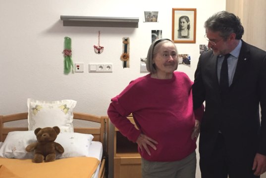 Inge Widowsky fühlt sich in ihrem neuen Zimmer im St. Lukas Pflegeheim sichtlich wohl. Franziskus von Ballestrem, Bereichsdirektor für die Senioreneinrichtungen der Kplus Gruppe, besucht die langjährige Bewohnerin in ihrem neuen Zuhause. (Foto: © Kplus Gruppe)