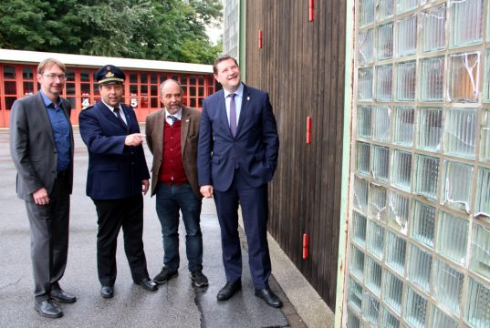 Die kaputten Glasbausteine sind nur ein äußerlich sichtbarer Teil der maroden Feuerwachen, wie hier in Wald am Frankfurter Damm. Ab 2021 wird deshalb neu gebaut. Ziehen dabei an einem Strang: v.li.: Dirk Chmel vom Planungsbüro Reichel, Feuerwehrchef Dr. Ottmar Müller, Ordnungsdezernent Jan Welzel und Oberbürgermeister Tim Kurzbach. (Foto: © B. Glumm)