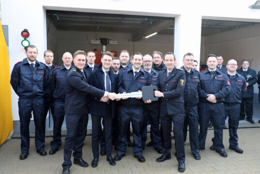 Symbolische Schlüsselübergabe zur Einweihung des Erweiterungsbaus: Oberbürgermeister Daniel Flemm mit dem symbolischen Schlüssel gemeinsam mit Feuerwehrleiter Sebastian Wagner und Einsatzkräften der Löscheinheit 8 Burg. (Foto: © Bastian Glumm)