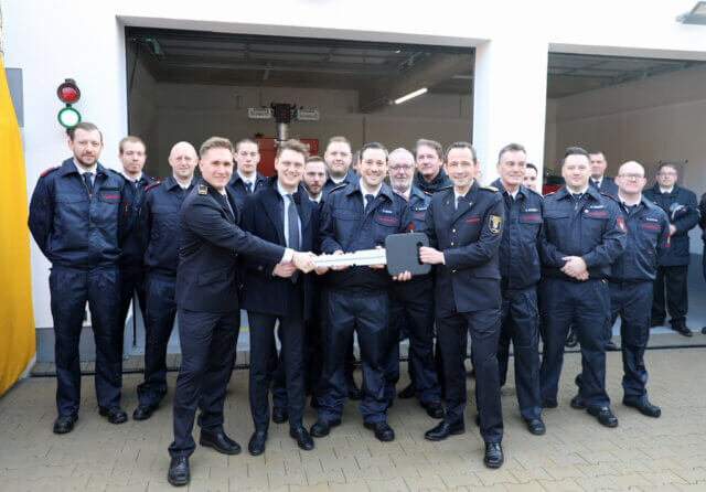 Symbolische Schlüsselübergabe zur Einweihung des Erweiterungsbaus: Oberbürgermeister Daniel Flemm mit dem symbolischen Schlüssel gemeinsam mit Feuerwehrleiter Sebastian Wagner und Einsatzkräften der Löscheinheit 8 Burg. (Foto: © Bastian Glumm)