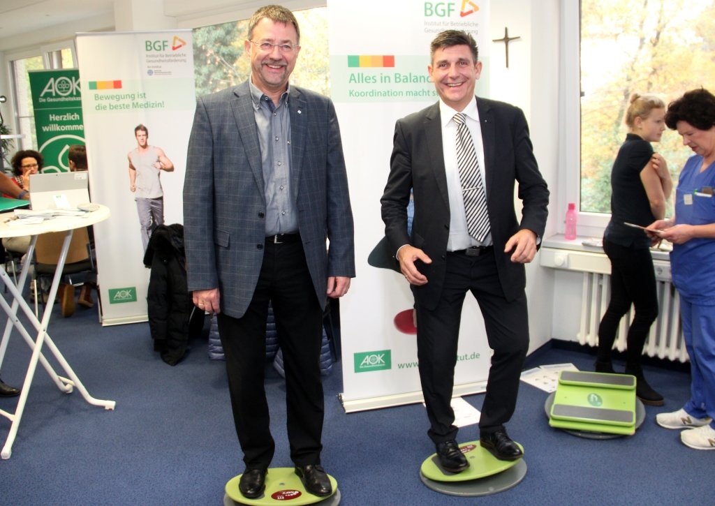 Gregor Hellmons (links), Sprecher der Geschäftsführung der Kplus Gruppe, und Oliver Hartmann (rechts), Regionaldirektor der AOK, versuchen sich auf dem Bewegungsparcour im Kplus Forum Solingen. (Foto: © Bastian Glumm)