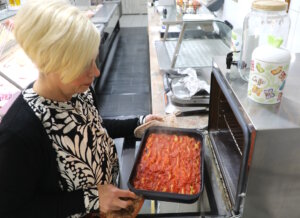 Im italienischen Supermarkt entstehen täglich frische Spezialitäten – hier bereitet Diega Zito ofenwarme Cannelloni mit Tomatensauce zu. (Foto: © Bastian Glumm)