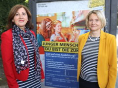 Maria Ricchiuti (li.) und Kristin Degener vom Kommunalen Jobcenter vor einem City-Light-Poster der Kampagne. Die Poster sind seit Dienstag an Bushaltestellen im Stadtgebiet angebracht. (Foto: © Bastian Glumm)