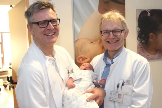 Haben gut lachen: Dr. Sebastian Hentsch (li.), Chefarzt der Klinik für Frauenheilkunde und Geburtshilfe und Dr. Volker Soditt, Chefarzt der Klinik für Kinder und Jugendliche im Klinikum. Der kleinen Schlafmütze im Baby-Schlafsack war der Presserummel am Freitagnachmittag sichtlich egal. (Foto: B. Glumm)