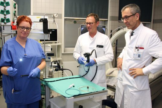 Prof. Dr. Wolfgang Schwenk (re.), Chefarzt der Klinik für Allgemein- und Viszeralchirurgie, und Prof. Dr. Boris Pfaffenbach, Chefarzt der Klinik für Gastroenterologie, Onkologie und Allgemeine Innere Medizin am Klinikum, setzen das "SpyGlass" erfolgreich in der Endoskopie ein. Endoskopie-Mitarbeiterin Stefanie Heußen-Sürig präsentiert die winzige Kamera. (Foto: © Bastian Glumm)