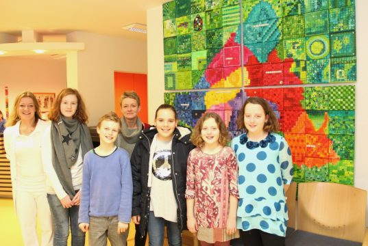 Freuen sich über den neuen Standort des Kunstwerkes in der Poliklinik des Klinikums: Anästhesieärztin Dr. Eva Bucher (li.), Künstlerin Heike Buschkotte-Leichsenring (4.v.li.) und die Schüler (v.li.) Lea, Leo, Franziska, Nele und Jule. (Foto: © Bastian Glumm)