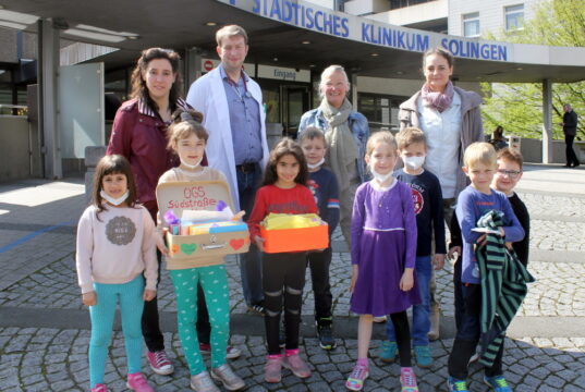 Laura Soawe (li.) und Yvonne Steinküller (2.v.re.) übergeben gemeinsam mit den Kids der OGS Südstraße die Grußkarten an Chefarzt Dr. Sven Propson und SPZ-Psychologin Sandra Kratz. (Foto: © Klinikum Solingen)