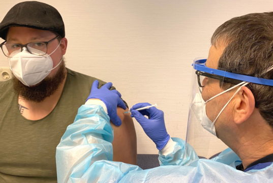 Andreas Fornaroli, Intensivpfleger der Lukas Klinik, gehört zu den ersten Mitarbeitenden, die sich von Dr. Bernhard Platz, Chefarzt der ZAE, impfen ließen. Insgesamt werden immer drei Ärzte parallel impfen bis die 144 zur Verfügung stehenden Impfdosen für die erste Mitarbeitergruppe verimpft sind. (Foto: © Kplus Gruppe)