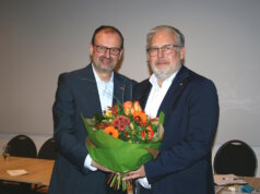 Arnd Krüger (li.) gratuliert seinem Nachfolger Marc Robert Clemens und überreichte ihm zum Amtsantritt als Kreishandwerksmeister einen Blumenstrauß. (Foto: © Kreishandwerkerschaft Solingen-Wuppertal)