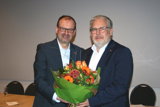 Arnd Krüger (li.) gratuliert seinem Nachfolger Marc Robert Clemens und überreichte ihm zum Amtsantritt als Kreishandwerksmeister einen Blumenstrauß. (Foto: © Kreishandwerkerschaft Solingen-Wuppertal)