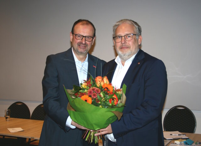 Arnd Krüger (li.) gratuliert seinem Nachfolger Marc Robert Clemens und überreichte ihm zum Amtsantritt als Kreishandwerksmeister einen Blumenstrauß. (Foto: © Kreishandwerkerschaft Solingen-Wuppertal)