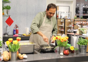 Dominic Gerberding kocht live am Stand von Küchenprofi auf der Ambiente 2026 und demonstriert den Einsatz der gezeigten Küchenwerkzeuge vor Fachbesuchern. (Foto: © Bastian Glumm)