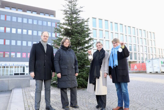 Von links: Dr. Guido Eusani und Nicole von Mueller (Mitteschmiede), Lorena Glatz (Stadt-Sparkasse Solingen) und Ulrike Kilp (Diakonie Solingen) vor dem erstmals auf dem Neumarkt aufgestellten Weihnachtsbaum. (Foto: © Bastian Glumm)