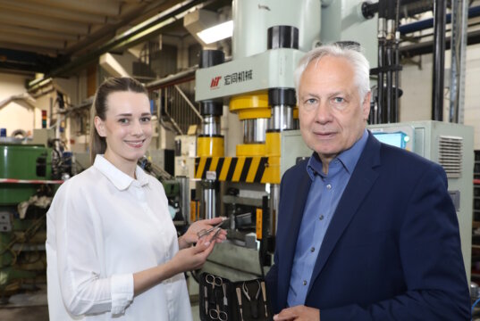 Vom Rohstahl zum fertigen Etui: Geschäftsführer Torsten Korb und Julia Nippes (Head of Sales) mit einem Niegeloh-Maniküre-Set vor einer Presse in der Solinger Produktion. (Foto: © Bastian Glumm)