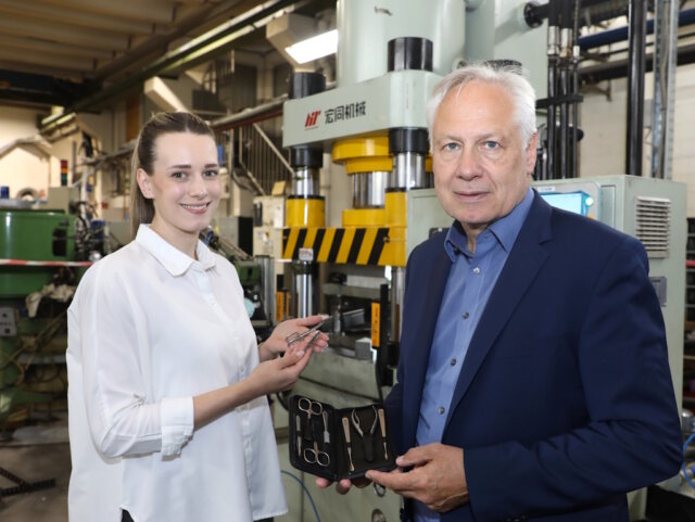 Vom Rohstahl zum fertigen Etui: Geschäftsführer Torsten Korb und Julia Nippes (Head of Sales) mit einem Niegeloh-Maniküre-Set vor einer Presse in der Solinger Produktion. (Foto: © Bastian Glumm)