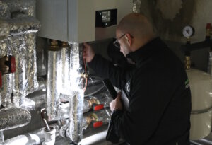 Kastriot Salihu bei der Feinjustierung der Anlage im Heizungskeller: Planung, Kontrolle und Abstimmung der Technik gehören bei NRG Heatpumps GmbH ebenso zum Projekt wie die Konzeption selbst. (Foto: © Bastian Glumm)