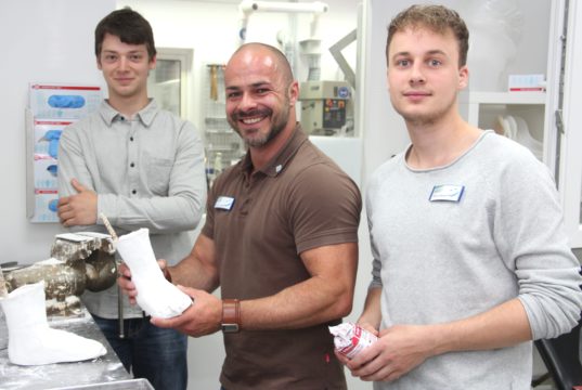 Sascha Gevelhoff (mi.), Meister und Betriebsleiter im Sanitätshaus Köppchen, zeigt, wie es geht. Die beiden Azubis Nils (li.) und Morris schauen ihm dabei über die Schulter und legen auch selbst Hand an. (Foto: © B. Glumm)