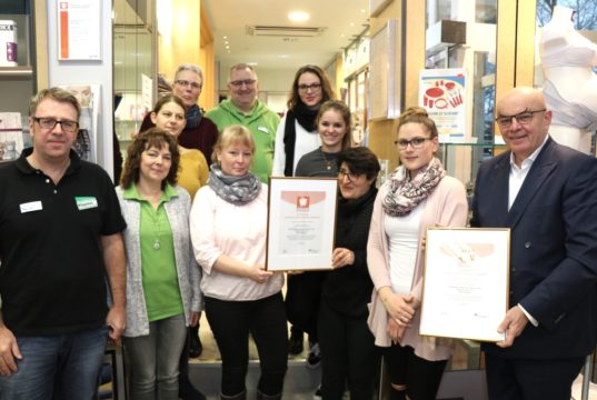 Ralf Engel (re.) vom Handelsverband Nordrhein-Westfalen – Rheinland e.V. brachte den Mitarbeiterinnen und Mitarbeitern des Sanitätshauses Köppchen am Dienstag die Re-Zertifizierung für das Gütesiegel „Generationenfreundliches Einkaufen“. (Foto: © Bastian Glumm)