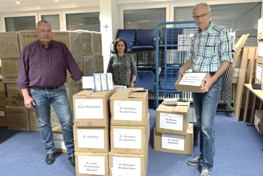 Der Leiter des Zentraleinkaufs Martin Steffen (re.), seine Mitarbeiterin Michaela Engels und Personalsachbearbeiter Manfred Kaiser halfen dabei, Pakete mit Mundschutzen für die verschiedenen Kplus-Einrichtungen zu packen. (Foto: © Kplus Gruppe)
