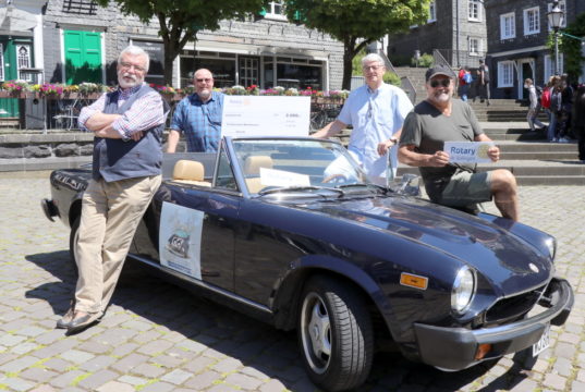 Friedensdorf-Botschafter Uli Preuss (li.) und Teamkollege Jürgen Beu (re.) nehmen mit einem Fiat Spider an der Six Bridges Rally teil. Eine Spende für das Friedensdorf in Höhe von 2.000 Euro überreichten jetzt Marc Schneider (2.v.l.) und Rene Splitthoff vom Rotary Club Solingen. (Foto: © Bastian Glumm)