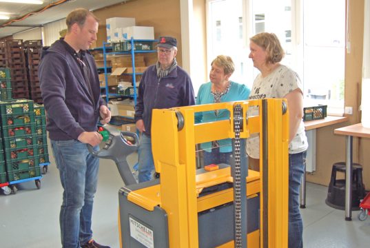 Vorwärts, rückwärts, lenken, heben und senken: Der Stapler steuert sich über multifunktionale Tasten an der Deichsel. Torsten Mitschelin erklärte die Handhabung Werner Fischer, der Tafel-Vorsitzenden Brigitte Funk und Alexandra Krug. Frau Krug wird auf den sachgerechten Umgang mit der im Wortsinn "entlastenden" Spende nun achten. (Foto: © Solinger Tafel)