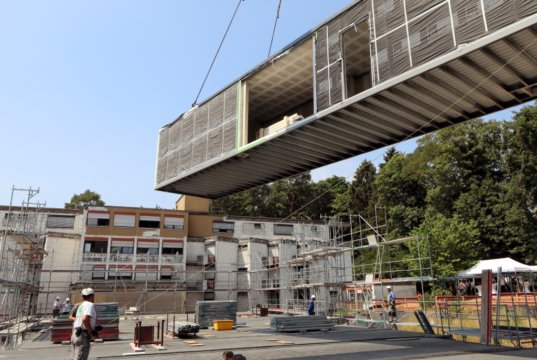 Im St. Joseph Altenheim an der Langhansstraße in Ohligs schwebten jetzt ganze Zimmer für den Neubau ein. Während eines kleinen Empfangs wurden die ersten Raummodule für den ersten Teilbau der Ohligser Senioreneinrichtung begrüßt. (Foto: © Kplus Gruppe)