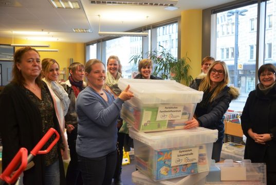 Mit strahlenden Gesichtern nehmen die Mitarbeiterinnen und Mitarbeiter der Einrichtungen ihre gut gefüllten Medienkisten entgegen. Die Boxen sollen Flüchtlingskindern den Zugang zur deutschen Sprache erleichtern. (Foto: © M. Hörle)