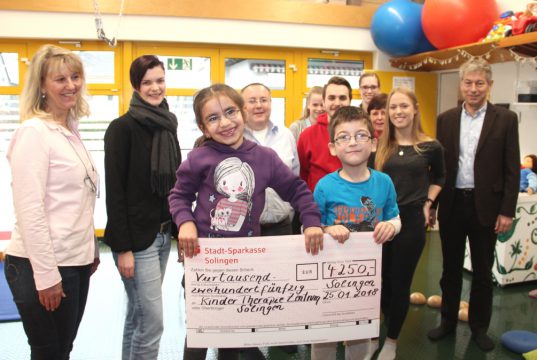 Grund zur Freude hatte am Donnerstag Carmen Erber (li.) von der Geschäftsführung des Kinder-Therapie-Zentrums, denn Andreas Schwarberg (re.), Vorsitzender der Geschäftsführung der Stadtwerke Solingen (SWS), kam mit SWS-Unternehmenssprecherin Lisa Nohl (2.v.li.) sowie Mitarbeitern und Azubis der Stadtwerke an die Weyerstraße und hatte einen Scheck im Gepäck. Darüber freuten sich natürlich auch Eli und Nicolo (beide sechs Jahre alt). (Foto: © Bastian Glumm)