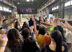 Gemeinsames Zeichen der Hoffnung: Besucherinnen und Besucher halten blaue Lichter in die Höhe – als stiller Abschluss der Theateraufführung „Liebe, Glaube, Frieden, Hoffnung“. (Foto: © Helfende Schirme Solingen)