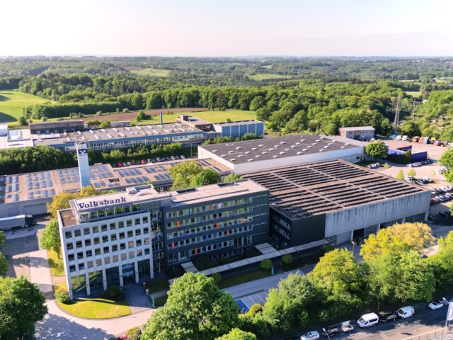 default Die Hauptverwaltung der Volksbank im Bergischen Land liegt am Rand von Remscheid-Lennep. Die PV-Anlage rechts neben dem Verwaltungstrakt wurde bereits 2013 gebaut. Die neue Anlage aus dem Jahr 2025 wurde auf der Dachfläche hinter dem Turm errichtet. (Foto: © Volksbank/Matthias Morawetz)