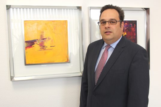 Ralf Wichmann (50) arbeitet seit 1994 für die Volksbank und ist seit zehn Jahren für den Bereich „Private Banking“ zuständig. Hier steht er vor zwei Werken des Solinger Künstlers Sascha Reichert, die in den Räumen der Volksbankfiliale an der Kölner Straße ausgestellt sind. (Foto: © B. Glumm)